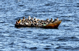 Migrants of African origin trying to flee to Europe are crammed on board of a small boat, as Tunisian coast guards prepare to transfer them onto their vessel, at sea between Tunisia and Italy, on August 10, 2023. Mediterranean Sea crossing attempts from Tunisia have multiplied following a incendiary speech by the Tunisian president who had alleged that "hordes" of irregular migrants were causing crime and posing a demographic threat to the mainly Arab country. -- Photo: Fethi Belaid / AFP