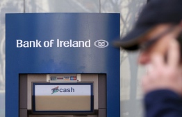 (FILES) A man walks past an ATM cash machine at a branch of a Bank of Ireland bank in Belfast, Northern Ireland, on March 31, 2010. Bank of Ireland apologised on August 16, 2023, after fixing a technical issue that allowed customers to withdraw or transfer more money than was in their accounts. The glitch saw large queues form at some cash machines on Tuesday and into the night, as word spread on social media, prompting police to be called in. (Photo by PETER MUHLY / AFP)