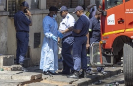 EDITORS NOTE:  / A man wearing forensic clothes speaks to a member of the South African Police Service (SAPS) in Johannesburg on August 31, 2023. More than 70 people have died in a fire that engulfed a five-storey building in central Johannesburg on August 31, 2023, the South African city's emergency services said. -- Photo: Guillem Sartorio / AFP