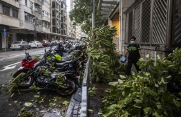 A woman walks past fallen tree branches due to strong winds from Super Typhoon Saola in Hong Kong on September 1, 2023. Super Typhoon Saola threatened southern China on September 1 with some of the strongest winds the region has endured, forcing the megacities of Hong Kong and Shenzhen to effectively shut down. -- Photo: Isaac Lawrence / AFP