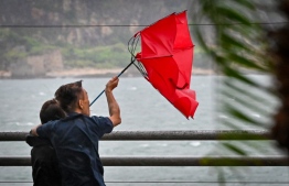 People struggle with their umbrella in high winds brought by Super Typhoon Saola in Heng Fa Chuen in Hong Kong on September 1, 2023. Super Typhoon Saola threatened southern China on September 1 with some of the strongest winds the region has endured, forcing the megacities of Hong Kong and Shenzhen to effectively shut down. -- Photo: Mladen Antonov / AFP