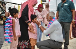 Dr. Muizzu interacting with a young child at the row of people waiting to welcome him to Baa Kamadhoo. -- Photo: PPM