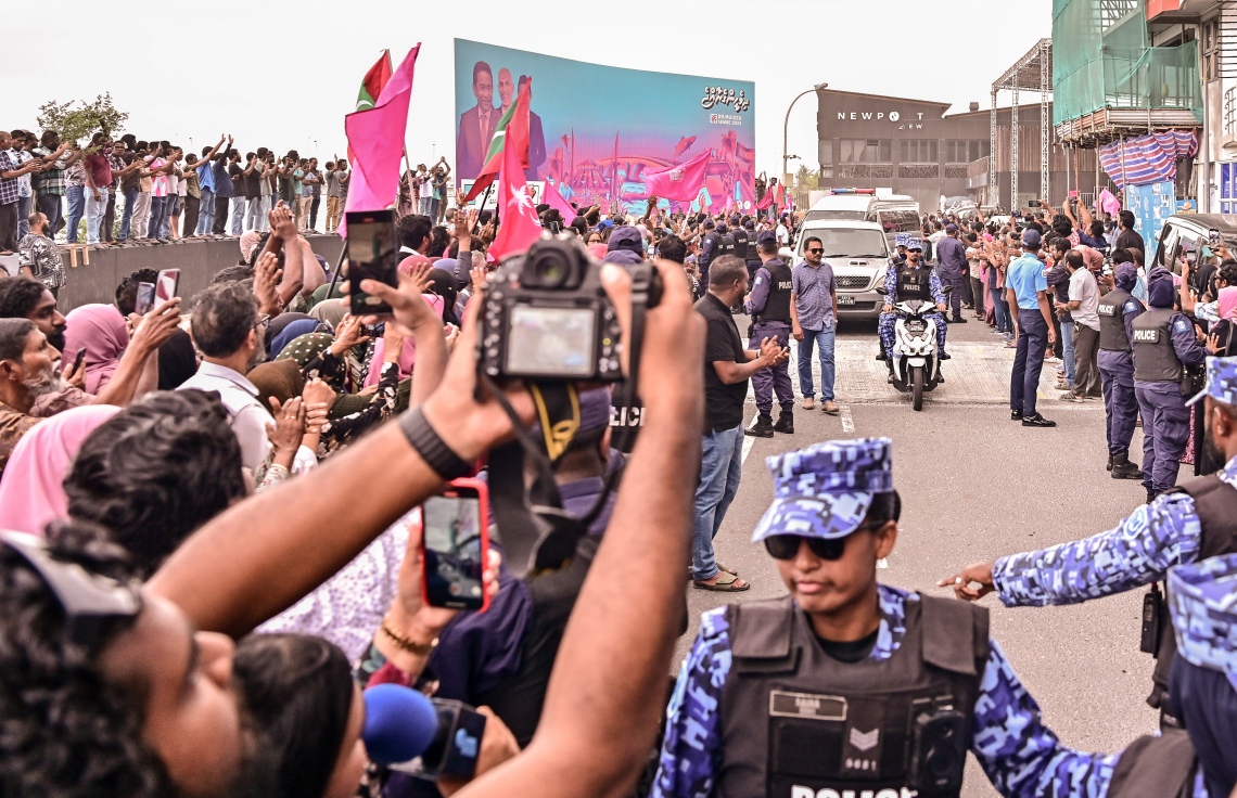 ކަރެކްޝަނަލް ސާވިސްގެ އޮފިސަރުންގެ ބެލުމުގެ ދަށުން ކުރީގެ ރައީސް ޔާމީން ޖަލުން ގޭ ބަންދަށް ގެންދާއިރު ފުލުހުން ސަލާމަތީ ކަންކަން ބަލަހައްޓަނީ: ޔާމީނަށް މަރުހަބާ ކިޔަން އެތައް ސަތޭކަ ބަޔަކު އެ މަނިކުފާނުގެ ގެކޮޅު ކައިރި އަށް ޖަމާވި. ޔާމީނަށް އިސްވެ މަރުހަބާ ދެންނެވީ އިންތިހާބީ ރައީސް ޑރ. މުހައްމަދު މުއިއްޒު.---ފޮޓޯ: ނިޝާން އަލީ| މިހާރު