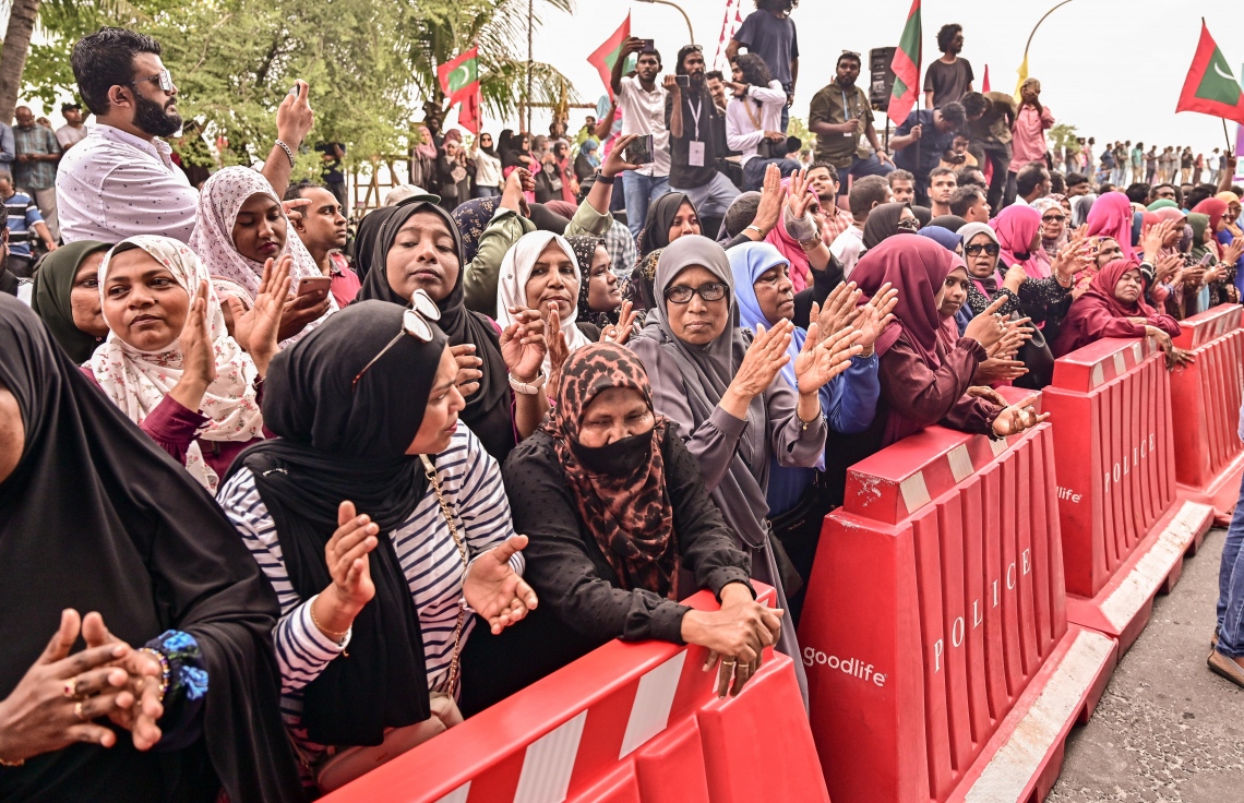 ކުރީގެ ރައީސް ޔާމީން ޖަލުން ގޭ ބަންދަށް ބަދަލުކުރުމުން ގެކޮޅަށް ވަޑައިގަންނަވާ ވަގުތެއްގެ އިންތިޒާރުގައި ސަޕޯޓަރުންތައް އެއްވެފައި: ޔާމީނަށް މަރުހަބާ ކިޔަން އެތައް ސަތޭކަ ބަޔަކު އެ މަނިކުފާނުގެ ގެކޮޅު ކައިރި އަށް ޖަމާވި. ޔާމީނަށް އިސްވެ މަރުހަބާ ދެންނެވީ އިންތިހާބީ ރައީސް ޑރ. މުހައްމަދު މުއިއްޒު.---ފޮޓޯ: ނިޝާން އަލީ| މިހާރު