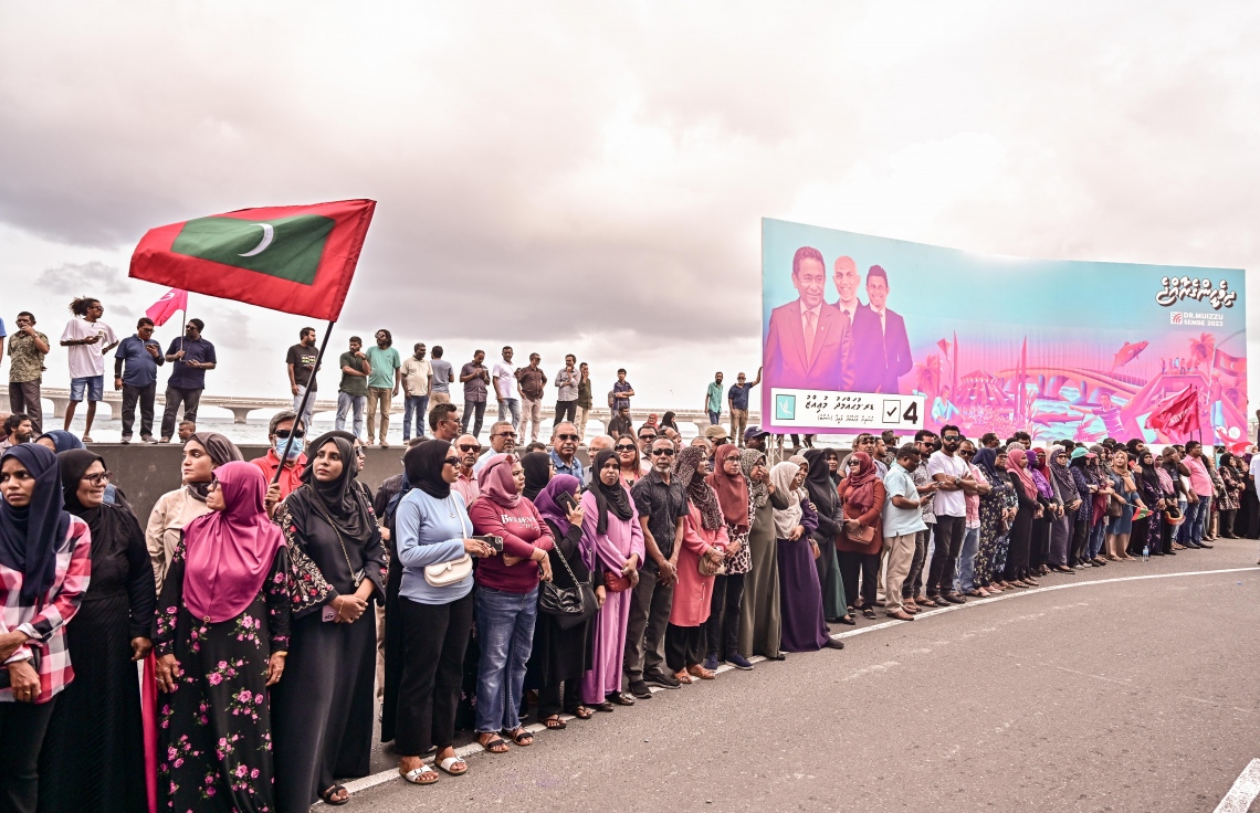 ކުރީގެ ރައީސް ޔާމީން ޖަލުން ގޭ ބަންދަށް ބަދަލުކުރުމުން ގެކޮޅަށް ވަޑައިގަންނަވާ ވަގުތެއްގެ އިންތިޒާރުގައި ސަޕޯޓަރުންތައް އެއްވެފައި: ޔާމީނަށް މަރުހަބާ ކިޔަން އެތައް ސަތޭކަ ބަޔަކު އެ މަނިކުފާނުގެ ގެކޮޅު ކައިރި އަށް ޖަމާވި. ޔާމީނަށް އިސްވެ މަރުހަބާ ދެންނެވީ އިންތިހާބީ ރައީސް ޑރ. މުހައްމަދު މުއިއްޒު.---ފޮޓޯ: ނިޝާން އަލީ| މިހާރު