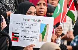 A woman holding a poster in the walk for Palestine Maldivians had on Friday, October 13, 2023: Maldives government called on Israel to reverse the evacuation order they issued to the civilians living in East Gaza -- Photo: Fayaz Moosa / Mihaaru