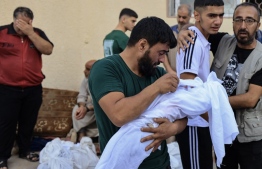 Man carries child killed in Israel air strikes.- Photo: AFP
