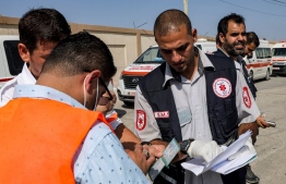 Palestinian health ministry paramedics check the travel documents of a person waiting to cross to Egypt at the Rafah border crossing in the southern Gaza Strip on November 1, 2023. Scores of foreign passport holders trapped in Gaza started leaving the war-torn Palestinian territory on November 1 when the Rafah crossing to Egypt was opened up for the first time since the October 7 Hamas attacks on Israel, according to AFP correspondents. -- Photo: Mohammed Abed / AFP