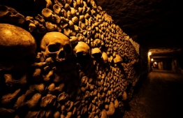 This photograph taken on December 12, 2023 shows human skulls and bones aligned against a wall of Paris' Catacombs, the cities former quarries where the remains of some six million people where transferred from saturated Parisian cemeteries between the end of the 18th century until 1861. -- Photo: Julieb De Rosa / AFP