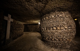 This photograph taken on December 12, 2023, shows human skulls and bones aligned against a wall of Paris' Catacombs, the city's former quarries where the remains of some six million people where transferred from saturated Parisian cemeteries between the end of the 18th century until 1861. -- Photo: Julien De Rosa / AFP