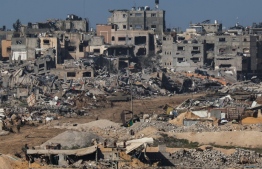 A picture taken from southern Israel bordering the Gaza Strip on December 22, 2023, shows an Israeli army tank rolling past debris of buildings in the Gaza Strip amid ongoing battles with the Hamas militant group. -- Photo: Jack Guez / AFP