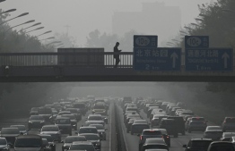 (FILES) Pedestrians walk on an overpass as traffic snarls amid haze from air pollution in Beijing on November 1, 2023. China's air pollution worsened in 2023, the first time it has done so in a decade, a study released on December 22, 2023 said. -- Photo: Pedro Pardo / AFP