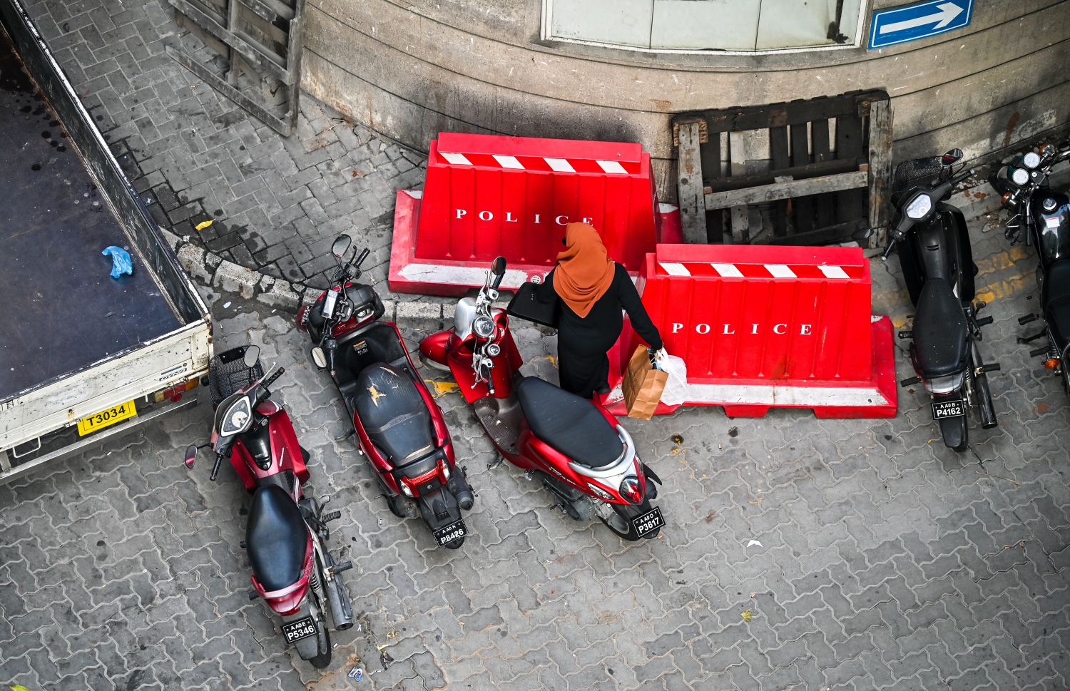 ގަވާއިދާ ހިލާފަށް ޕާކްކޮއްފައި ހުރި ސައިކަލްތަކެއް ކައިރިން މީހަކު ޕޭމަންޓަށް އަރަން މަސައްކަތްކުރަނީ،-- ފޮޓޯ؛ ފަޔާޒު މޫސާ | މިހާރު