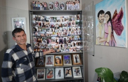 Mesut Hancer, stands infront of photographs of his 15-year-old-daughter Irmak, victim of the earthquake that hit Turkey's southeast on February 6, 2023, during an interview in Ankara on January 11, 2024. Mesut Hancer's dead daughter's hand in his, his gaze floating above the rubble: with his photo broadcast around the world, Hancer symbolizes the grief of the victims of the earthquake in Turkey, which has claimed more than 50,000 lives. (Photo by Adem ALTAN / AFP)