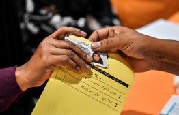 A voter being handed their ID card and voting ballot to vote for Baa atoll Hithadhoo constituency on February 3, 2024 -- Photo: Fayaz Moosa