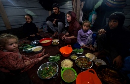 Palestinians prepare for an "iftar" meal, breaking of fast, on the second day of the Muslim holy fasting month of Ramadan, at a camp for displaced people in Rafah in the southern Gaza Strip on March 12, 2024. -- Photo by Mohammed Abed / AFP