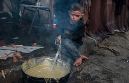 A Palestinian boy waits for an "iftar" meal, breaking of fast, on the second day of the Muslim holy fasting month of Ramadan, at a camp for displaced people in Rafah in the southern Gaza Strip on March 12, 2024, amid ongoing battles between Israel and the militant group Hamas. -- Photo by Mohammed Abed / AFP