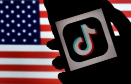 (FILES) In this photo illustration, the social media application logo, TikTok is displayed on the screen of an iPhone on an American flag background on August 3, 2020 in Arlington, Virginia. The US House of Representatives overwhelmingly approved a bill on March 13, 2024 that would force Tiktok to divest from its Chinese owner or get banned from the United States. -- Photo: Olivier Douliery / AFP