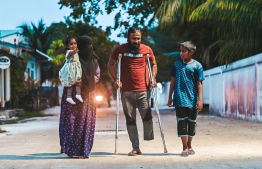 Ibrahim Mohamed, accompanied by his wife and kids outside his home in Thaa Atoll Hirilandhoo.-- Photo: Fayaz Moosa / Mihaaru