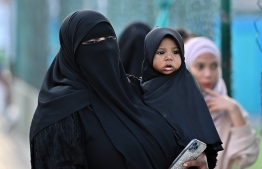 Woman and child attend Eid prayers.-- Photo: Nishan Ali / Mihaaru