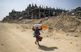 A child carrying salvaged items walks past the rubble of buildings destroyed during Israeli bombardment in Khan Yunis, on the southern Gaza Strip on April 16, 2024, as fighting continues between Israel and the Palestinian militant group Hamas. --Photo: AFP