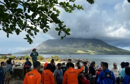 This handout from Indonesia's National Search and Rescue Agency (BASARNAS) received on April 18, 2024 shows people in Sitaro, North Sulawesi looking at the Mount Ruang volcano, as it spews smoke. Indonesian rescuers raced to evacuate thousands of people on April 18 after the volcano erupted five times, forcing authorities to close a nearby airport and issue a warning about falling debris that could cause a tsunami. -- Photo: National Search and Rescue Agency (BASARNAS) / AFP)