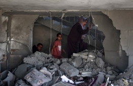 A Palestinian woman and children check the rubble of a building hit by overnight Israeli bombing in Rafah in the southern Gaza Strip on April 20, 2024, amid the ongoing conflict between Israel and the Hamas movement. (Photo by AFP)