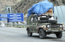 An Armenian resident of Nagorno-Karabakh drives past Azerbaijani border guard servicemen after being checked at the Lachin checkpoint on the way to Armenia, in Azerbaijan. -- Photo: AP
