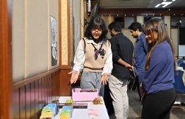 A student displaying her work to a visitor at the exhibition.