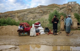 Afghan men stand beside their belongings kept near a damaged house after flash floods following heavy rainfall in Firozkoh, Ghor province on May 18, 2024. Flash flooding has killed at least 50 people in western Afghanistan, provincial police said on May 18, a week after hundreds were washed away in the north of the country. -- Photo: AFP