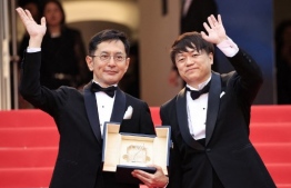 Vice President of Events and exhibitions, Studio Ghibli Kenichi Yoda waves next to Japanese director and Ghibli Park Creative Development manager Goro Miyazaki as he holds the Honorary Palme d’or after ceremony at the 77th edition of the Cannes Film Festival in Cannes, southern France, on May 20, 2024. -- Photo: Valery Hache / AFP