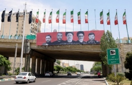 Cars drive past a billboard bearing a portrait of Iran's late president Ebrahim Raisi (C), his foreign minister Hossein Amir-Abdollahian (2nd L) and other members of his entrourage in central Tehran, on May 21, 2024, as mourners in the northestern city of Tabriz attended a funeral procession for the president and seven others who were killed with him in a helicopter accident two days ago. Raisi was confirmed dead along with his foreign minister and six others on May 20, 2024, after search and rescue teams found their crashed helicopter in a fog-shrouded mountain region in Iran's East Azerbaijan province, sparking mourning in the Islamic republic. -- Photo: Atta Kenare / AFP