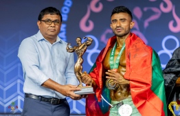 Minister of State for Sports, Fitness and Recreation, Ibrahim Amir awarding Azneen with his gold medal and trophy during the Championship. -- Photo: Ministry of Sports, Fitness and Recreation
