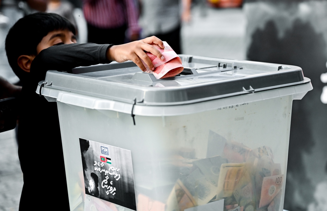 "ފަލަސްތީނާ އެކު ދިވެހީން" ނަމުގައި ދައުލަތުގެ މީޑިއާ ޕީއެސްއެމުން އިންތިޒާމު ކޮށްގެން މިއަދު ކުރިއަށް ގެންދާ ޓެލެތޯންގައި ހުޅުވާފައިވާ ފަންޑު ފޮއްޓަކަށް ކުޑަކުއްޖަކު ރުފިޔާ ލަނީ.-- ފޮޓޯ: ނިޝާން އަލީ | މިހާރު