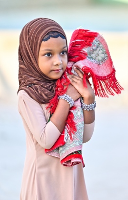 A little girl heading to the B.Kendhoo football stadium with a prayer mat to join the Eid-al-Adha prayer congregation today. -- Photo: Fayaz Moosa / Mihaaru News