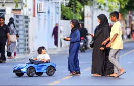 A family taking a toddler in a toy car out for a ride during the vehicle ban issued from 16:00 hrs to 18:00 hrs on occasion of Eid-al-Adha. -- Photo: Mihaaru News