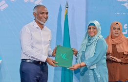 Owner of the PNC House premise, H. Veyo Villa, Shafiyya Zubair handing over her registration form to President Muizzu after signing into People's National Congress (PNC). -- Photo: PNC