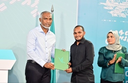 President Dr Mohamed Muizzu receiving the enrollment form of a new PNC member during the 'Haruge Ceremony' held at PNC House last night. -- Photo: Fayaz Moosa / Mihaaru News