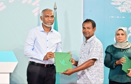 President Dr Mohamed Muizzu receiving the sign-up form of a new PNC member during the 'Haruge Ceremony' held at PNC House last night. -- Photo: Fayaz Moosa / Mihaaru News