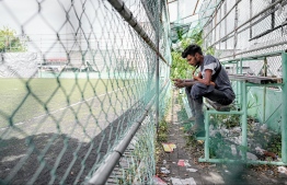 A man seated on the bench dedicated for spectators in an FAM Turf Ground which is also now in ruins. -- Photo: Nishan Ali / Mihaaru News