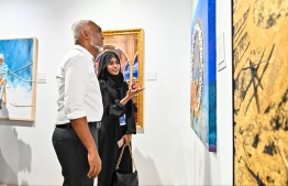 An artist whose artwork is featured at the art exhibition, Unveiling Vision, showing her artwork to President Dr Mohamed Muizzu. -- Photo: Fayaz Moosa / Mihaaru News