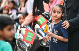 A child watching the MNDF parade held yesterday to commemorate Maldives' Independence Day with the national Maldivian flag. -- Photo: Fayaz Moosa / Mihaaru News