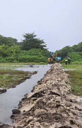 Using an excavator to cut paths in streets in an attempt to have the flood water drain into the sea.