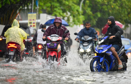 Motorcycle drivers travelling on Ameenee Magu which was heavily flooded due to the relentless rain on Tuesday. -- Photo: Fayaz Moosa / Mihaaru News