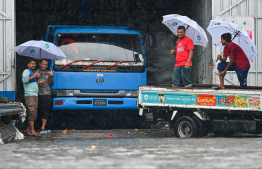 Workers active near a State Trading Organization (STO) warehouse yesterday; Many premises across the city had sustained damages due to relentless rain. -- Photo: Fayaz Moosa / Mihaaru News