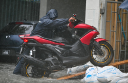 A driver attempting to avoid damages to his motorcycle due to the flash flood caused by heavy rain yesterday. -- Photo: Fayaz Moosa / Mihaaru News