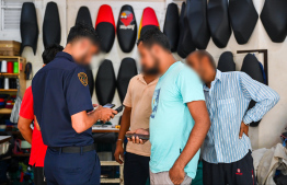 Immigration officers reviewing information of expats employed at a motorcycle maintenance store in capital, Male' during yesterday's operations. -- Photo: Fayaz Moosa / Mihaaru News