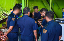 Immigration officers reviewing information of expats employed at a local shop in capital, Male' during yesterday's operations. -- Photo: Fayaz Moosa / Mihaaru News