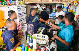 Immigration officers reviewing information of expats working at a local shop in capital, Male' during yesterday's operations. -- Photo: Fayaz Moosa / Mihaaru News