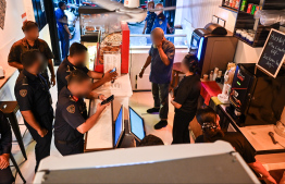 Immigration officers reviewing information of expats working at a cafe' in Chaandhanee Magu, Male' City during yesterday's operations. -- Photo: Fayaz Moosa / Mihaaru News